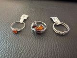 three silver rings with orange stones sitting on top of a black leather surface