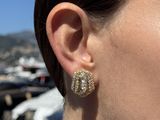 woman wearing a pair of gold tone earrings with a pearl and diamond center