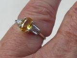 la main d'une personne tenant une bague sertie d'une pierre jaune