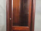 une armoire en bois avec une porte vitrée, placée dans un coin