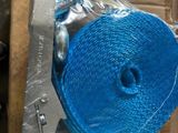 un rouleau de corde bleue emballé dans du plastique, posé sur une boîte