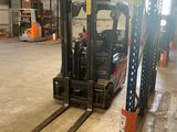 a forklift in a large warehouse with lots of pallets