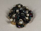 a close up of a brooch with pearls on it