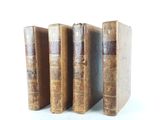 three old books are stacked on top of each other on a white surface