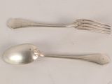 two silver spoons and a fork on a table