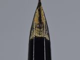 close up of the tip of a pen with a black tip and a gold tip