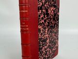un livre rouge à la couverture noire et rouge posé sur une surface blanche