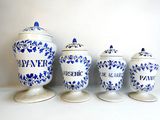 three blue and white canisters are lined up against a white wall