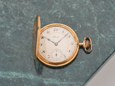 une montre de poche en or posée sur une surface en marbre