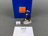 the figurine is sitting next to a blue box and a white piece of paper
