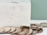 un bloc de marbre blanc posé sur une table, à côté d'une pile de pièces de monnaie