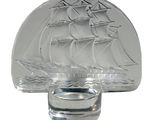 une bouteille en verre sur laquelle est représenté un bateau, à côté d'un bougeoir en verre