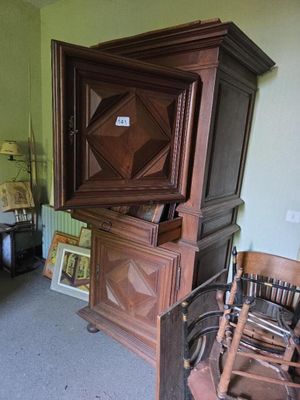 une armoire en bois dans un coin d'une pièce où se trouve un fauteuil à bascule