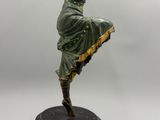 Une statue représentant une femme en robe verte se dresse sur un socle noir.