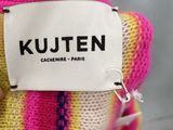 a person holding a knitted teddy bear with a label on it