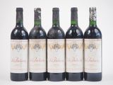 quatre bouteilles de vin rouge sont alignées sur une surface blanche