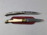 two knives and a cork opener on a red cloth