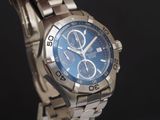 une montre en argent avec un cadran bleu sur fond noir