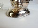 un bougeoir en argent posé sur une table à côté d'un verre