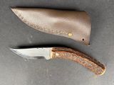 a knife and sheath on the table next to each other