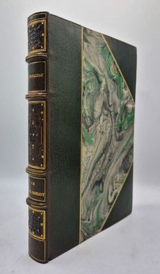 un vieux livre à la couverture verte posé sur une table blanche