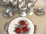 une assiette blanche ornée de roses rouges, à côté de tasses et de cuillères