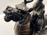 une statue représentant un homme chevauchant un taureau, avec un bouclier sur le dos