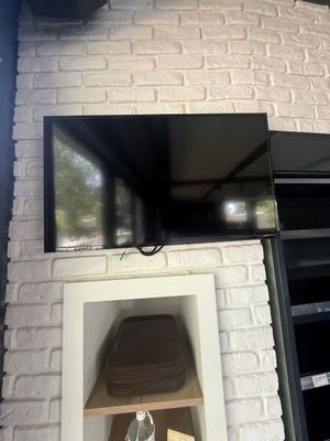 a television mounted on a brick wall above a fireplace