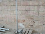 a wooden pallet sitting in front of a brick wall with a pipe sticking out of it