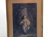 Une vieille photo représentant un jeune garçon en blouse blanche est exposée dans un cadre doré.