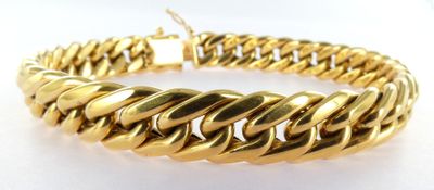 a close up of a gold bracelet on a white surface