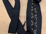 une ceinture noire ornée de boucles dorées posée sur une table en bois
