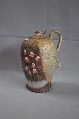 a brown vase with flowers on it sitting on a table