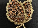 an image of a broochle of a leaf with crystals on it