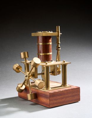 une petite maquette de machine à vapeur posée sur un socle en bois