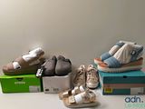plusieurs paires de chaussures pour bébé posées sur des cartons, sur une table