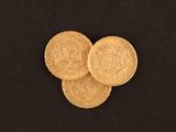 a close up of a pile of gold coins on a black surface