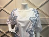 un mannequin portant une chemise blanche ornée de fleurs bleues