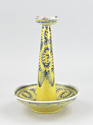 un vase jaune et bleu surmonté d'un oiseau