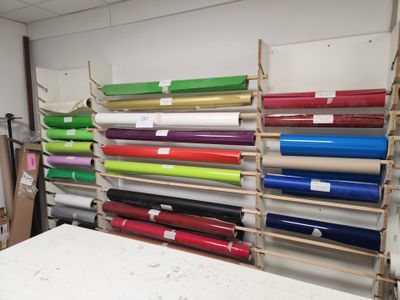 de nombreux rouleaux de papier coloré posés sur une étagère dans une pièce