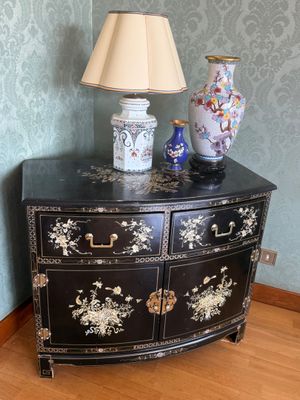 une commode noire sur laquelle est posée une lampe