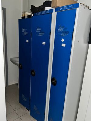 plusieurs casiers bleus dans une salle de bains équipée d'un lavabo et de toilettes