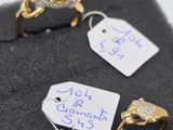 two gold rings with diamonds and a price tag on a black cloth