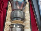 three silver cups and spoons sitting in a case