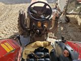 un tracteur rouge équipé d'un volant, immobilisé dans la terre