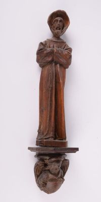 une statue en bois représentant une femme coiffée d'un chapeau, posée sur une étagère