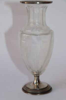 un vase en verre transparent avec un couvercle en argent, posé sur une table
