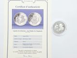 deux pièces d'argent et un certificat posés sur un fond blanc