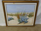 une peinture à l'huile représentant une scène de plage avec des fleurs bleues, dans un cadre doré