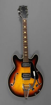 un gros plan d'une guitare électrique sur fond gris